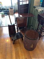 Photo of all items together showing butter churn, drop leaf cabinet, stool, plant stand, and decorative barrel on wooden floor.