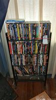 Front view of black metal DVD storage stand filled with DVDs.