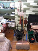 Photo showing fireplace tools including poker, shovel, brush, bellows, wood carriers, broom, and water canteen near fireplace