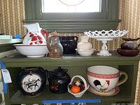 Wide view showing all lot items arranged on shelves including pitcher and basin, footed fruit bowl, handled bowl, teapot, urn, cup, and artificial fruit basket