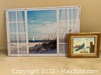 Two seascape art pieces shown side by side on carpeted floor. Large window scene print/canvas (approx 25x32 inches) and smaller framed seagull painting.