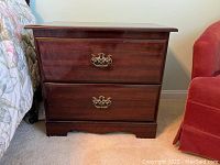 Front view of wooden cabinet showing two drawers with decorative brass handles and some wear marks.