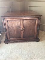 Front view of medium brown wood cabinet with double doors and metal pull handles