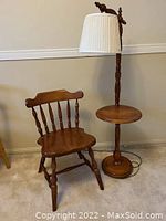 Photo showing full view of wooden chair and floor lamp with integrated table.