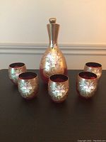 Full set of one glass decanter and five matching glasses showing floral decorative design and gold background
