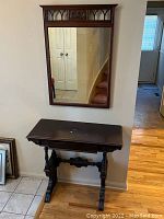 Full view of wooden entrance table beneath matching mirror on wall showing overall condition and wear