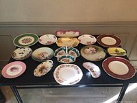 Top-down view of all 15 assorted decorative china plates and dishes arranged on table