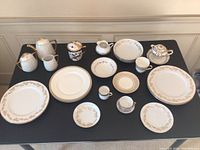 Full lot display of assorted china on black cloth.