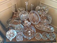 Full set of 15 various shaped crystal items arranged on table, showing bowl, plates, vases, and dishes with detailed cut glass patterns.