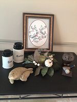 Photo showing all items together including framed bird print, owl figurine, sea lion figurine, kitchen canisters, floral arrangement, and small blue bird figurine
