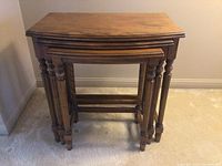 Front view showing all three wooden nesting tables stacked inside each other.