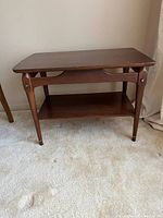 Front and side view of a wooden side table on a carpeted floor showing the structure and small scratches on legs.
