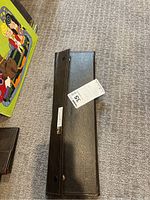 Black roll-up knife holder closed with attached label showing lot number