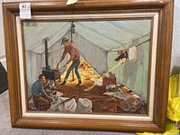 Full front view of framed painting showing cowboy scene inside a tent with two figures and various objects.