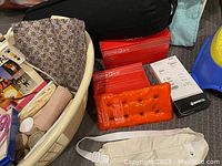 Photo showing the oval cream laundry basket containing all the items including SomaCare heat packs, heating pad in box, bandages, and pillow.