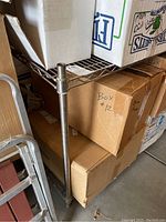 Close-up photo of metal wire shelf with cardboard boxes on it in a garage setting.
