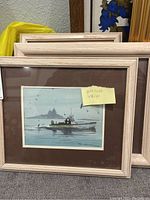 Photo of four framed watercolor paintings stacked, showing art with boats and seagulls on water, signed by John Hadock.