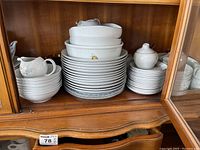 Two sets of stacked plates, bowls and a sugar bowl in a wooden hutch.