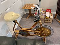 Side view of vintage Schwinn stationary exercise bike with padded white seat cushion in indoor setting.