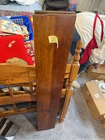 Finished wooden plank vertical view leaning against furniture, showing wood grain and condition.