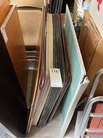 Top-down view showing the edges and varying surface materials and finishes of four vintage card tables stacked vertically.
