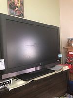 Front view of the black-framed Westinghouse television with visible large screen and built-in stand and surrounding furniture.