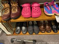 Two wooden shelves with ten pairs of women's shoes. Top shelf shows brown hiking boots, pink Crocs, and pink/blue casual shoes. Bottom shelf shows black flats, brown dress shoes, and black loafers.