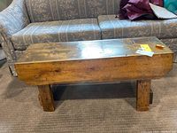 Front angled view of the rustic wooden bench showing the top surface and part of the legs.