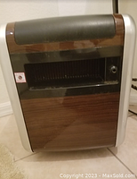 Photo shows a rectangular ceramic band heater with wood front panel, black top handle, and control knob on the side.