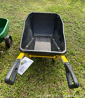 Front view of Gorilla Carts metal wheelbarrow showing yellow frame, black plastic tray and handles with grips.