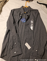 Full front view of black and white check long sleeve dress shirt on a yellow hanger showing button details and tags.