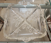 Top-down photo of the clear glass divided square bowl showing floral embossed details and four compartments separated by raised glass sections.