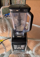 Front view of Ninja brand blender, showing clear blending pitcher with measurement markings and black base with control panel buttons.