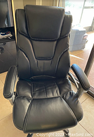 Front view of black executive office chair showing the padded seat, backrest, and armrests.