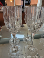 Close-up view of two vintage crystal wine glasses highlighting the etched lines and faceted stems.