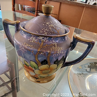 Vintage ceramic tripod sugar bowl with fruit and flower hand-painted decoration, with a lid and two handles.