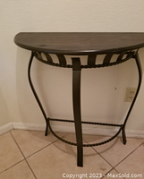 Side view of the half-moon shaped side table showing black metal legs and dark wood top.