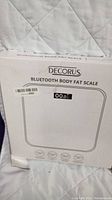 Photo of the Decorus Bluetooth Body Fat Scale original boxed packaging showing the product name, digital display, and icons.