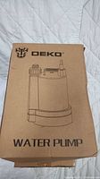 Brown cardboard box with DEKO brand logo and water pump illustration on the front, labeled 'WATER PUMP'.