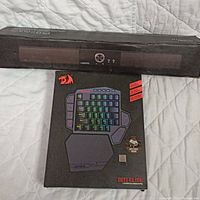 Photo showing Conrpo wireless soundbar in black packaging alongside Redragon Diti Elite gaming keyboard box with RGB keys and wrist rest image.