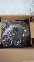 Box containing an 8-inch inline duct fan wrapped in plastic inside a cardboard box