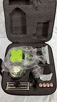 Lazor Square laser leveler and accessories arranged in black foam carrying case with clear plastic wrapping