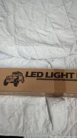 Boxed LED light bar on a quilted white fabric showing the label 'LED LIGHT BAR' and an off-road vehicle graphic.