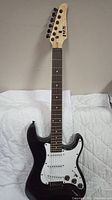 Front view of Lyx Pro electric guitar with black body and white pickguard, showing neck and headstock.