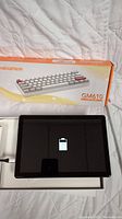 Front view of tablet screen showing battery icon with Newmen GM610 keyboard box behind