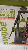 Close-up of the pressure washer box showing brand name Sun Joe, model SPX2608, and specifications including 2050 PSI max pressure, 1.2 GPM max flow, and electric powered.