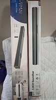 Two boxed soundbars standing side by side on a white cloth background. Boxes show images and feature descriptions of each soundbar model.