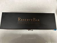 Top view of closed black wooden case with ReserveBar logo in gold lettering