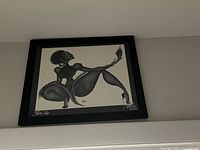 Full view of the framed drawing "Black Lily" by David Patterson hung on a neutral wall, showing the entire artwork and frame.