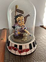 Front view of Betty Boop figurine under glass dome with piano key base and two smaller characters.